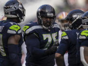 Seattle Seahawks offensive lineman Duane Brown talks with quarterback Russell Wilson, second from right, during an NFL football game against the San Francisco 49ers, Sunday, Dec. 5, 2021, in Seattle. The Seahawks won 30-23.