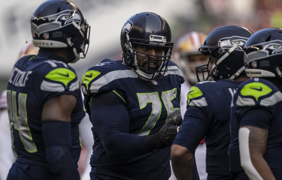 Seattle Seahawks offensive lineman Duane Brown talks with quarterback Russell Wilson, second from right, during an NFL football game against the San Francisco 49ers, Sunday, Dec. 5, 2021, in Seattle. The Seahawks won 30-23.