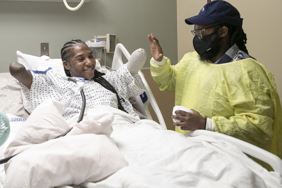 Candice Davis, 30, high-fives her brother, Ali Davis, in her hospital bed at Penn Presbyterian Medical Center in Philadelphia on Nov. 30, 2021. Davis had to have all her limbs partially amputated after a serious bout with COVID-19 in August. Davis has been in high spirits recently, accepting her new reality and journey moving forward.