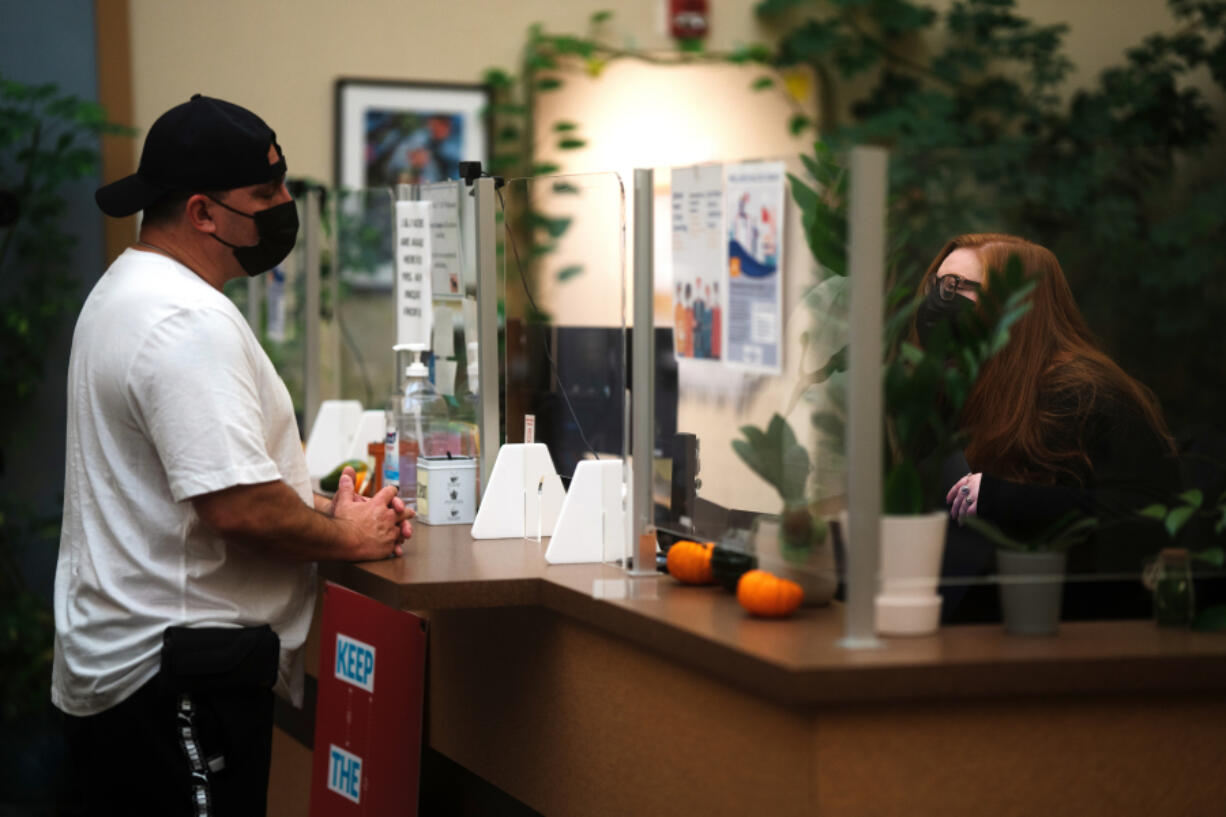 Peer specialist John Amato, left, chats with a receptionist at Columbia River Mental Health Services' NorthStar Clinic in central Vancouver on Dec. 14. Amato has lived experience with addiction. He helps patients navigate through recovery and connects them with resources.