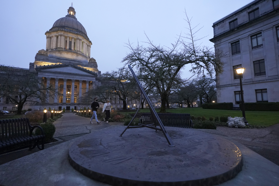 People walk past the sundial near the Legislative Building in Olympia just before dusk on Tuesday, the shortest day of the year. (ted s.