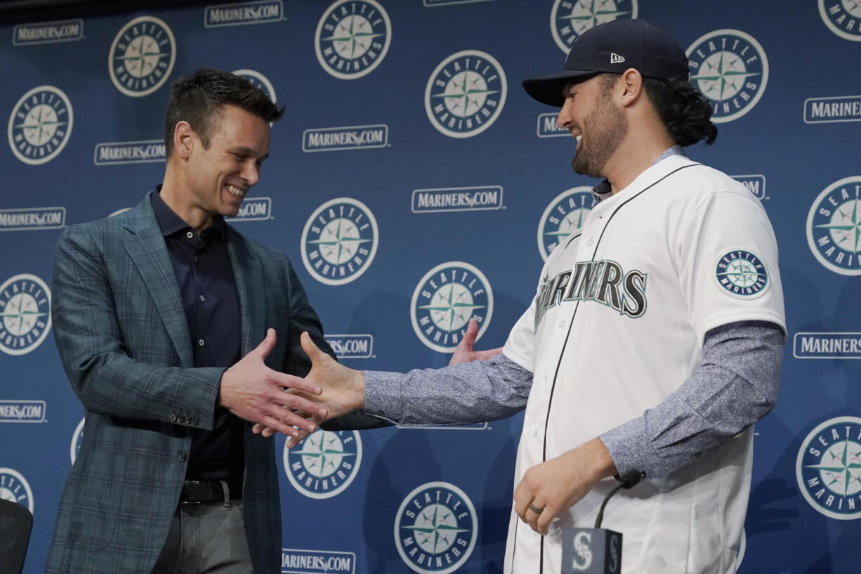 Jerry Dipoto, left, Seattle Mariners President of Baseball Operations, shakes hands with new Seattle Mariners pitcher Robbie Ray, right, Wednesday, Dec. 1, 2021, during a news conference in Seattle. The AL Cy Young Award winner — who previously pitched for the Toronto Blue Jays — signed a five-year contract with the Mariners. (AP Photo/Ted S.