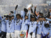 New York City FC players celebrate with the trophy after their penalty kick shootout win over the Portland Timbers in the MLS Cup soccer game, Saturday, Dec. 11, 2021, in Portland, Ore.