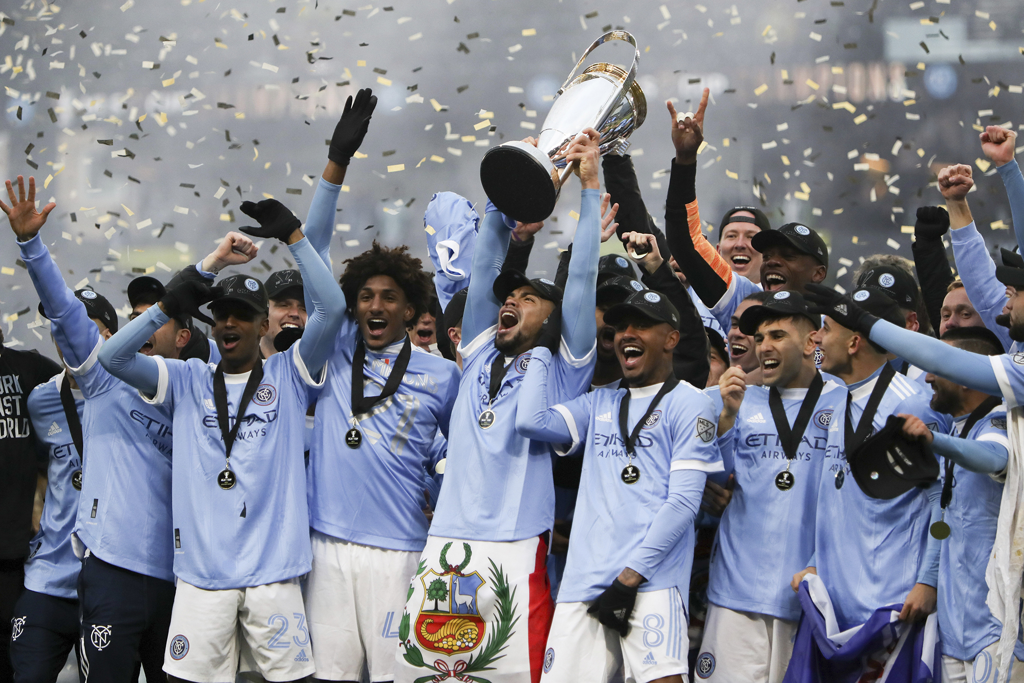New York City FC players celebrate with the trophy after their penalty kick shootout win over the Portland Timbers in the MLS Cup soccer game, Saturday, Dec. 11, 2021, in Portland, Ore.
