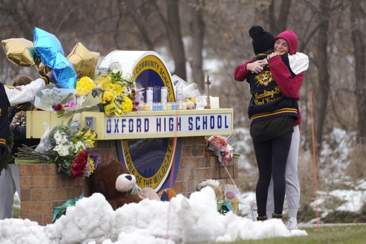 Students hug at a memorial at Oxford High School in Oxford, Mich., Wednesday, Dec. 1, 2021. Authorities say a 15-year-old sophomore opened fire at Oxford High School, killing four students and wounding seven other people on Tuesday.