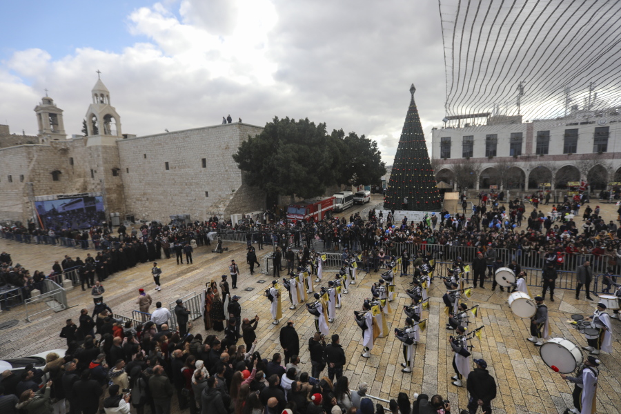 Palestinian scout bands parade through Manger Square at the Church of the Nativity, traditionally believed to be the birthplace of Jesus Christ, during Christmas celebrations, in the West Bank town of Bethlehem, Friday, Dec. 24, 2021. The biblical town of Bethlehem is gearing up for its second straight Christmas Eve hit by the coronavirus with small crowds and gray, gloomy weather dampening celebrations Friday in the traditional birthplace of Jesus.