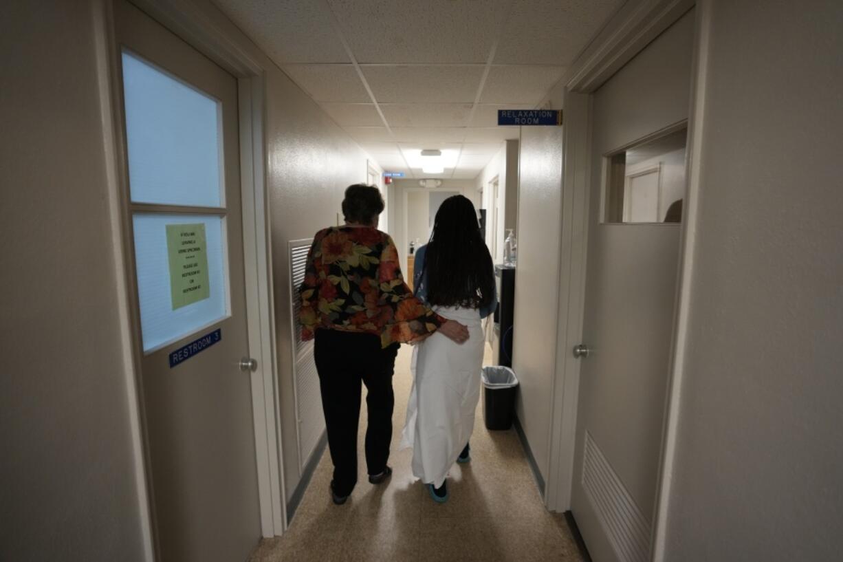 FILE - A 33-year-old mother of three from central Texas is escorted down the hall by clinic administrator Kathaleen Pittman prior to getting an abortion, Saturday, Oct. 9, 2021, at Hope Medical Group for Women in Shreveport, La. The woman was one of more than a dozen patients who arrived at the abortion clinic, mostly from Texas, where the nation's most restrictive abortion law remains in effect.