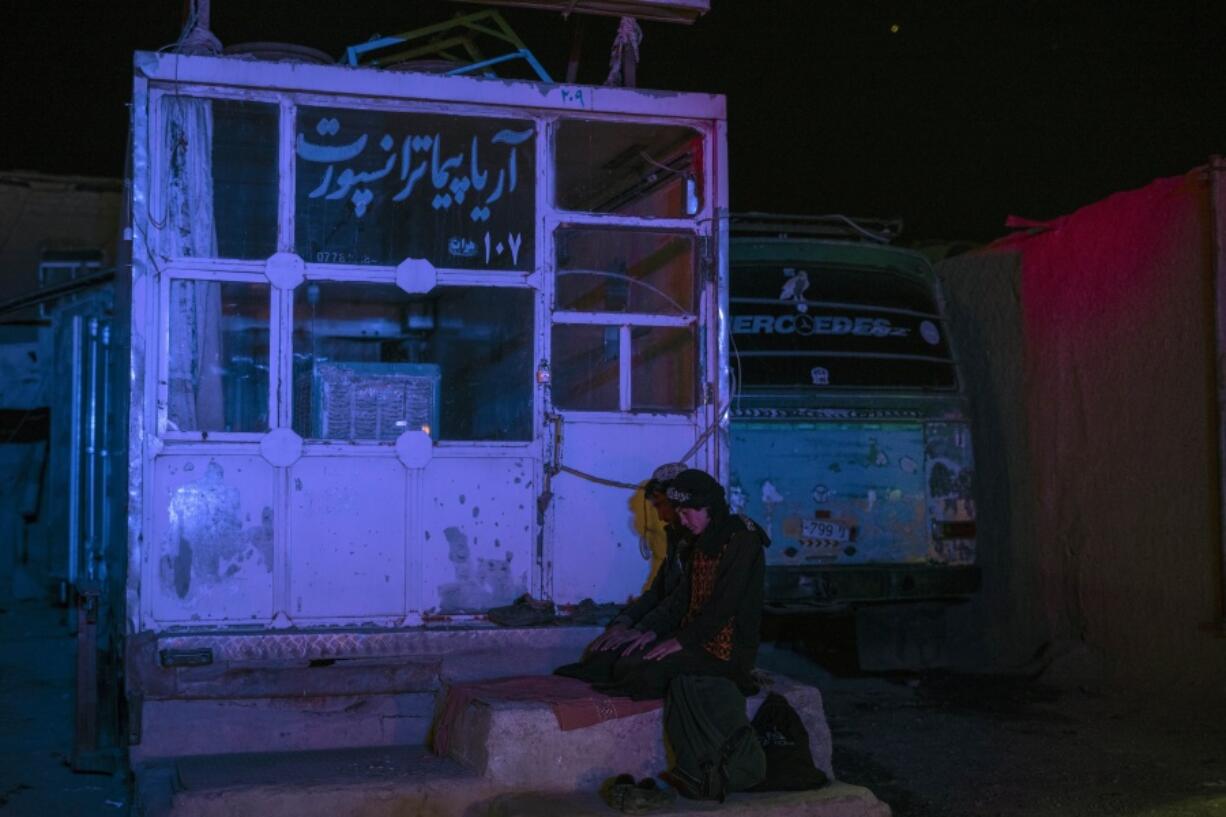 Two Afghan men pray at a bus station in Herat, Afghanistan, on Tuesday, Nov. 23, 2021, before they embark on a bus for a 300-mile trip south to Nimrooz near the Iranian border. Afghans are streaming across the border into Iran, driven by desperation after the near collapse of their country's economy following the Taliban's takeover in mid-August. In the past three months, more than 300,000 people have crossed illegally into Iran, according to the Norwegian Refugee Council, and more are coming at the rate of 4,000 to 5,000 a day.