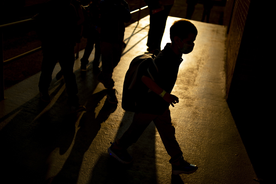 FILE - A student arrives as the sun rises during the first day of school on Wednesday, Aug. 4, 2021 at Freeman Elementary School in Flint, Mich. New autism numbers released Thursday, Dec. 2 suggest more U.S. children are being diagnosed with the developmental condition and at younger ages.