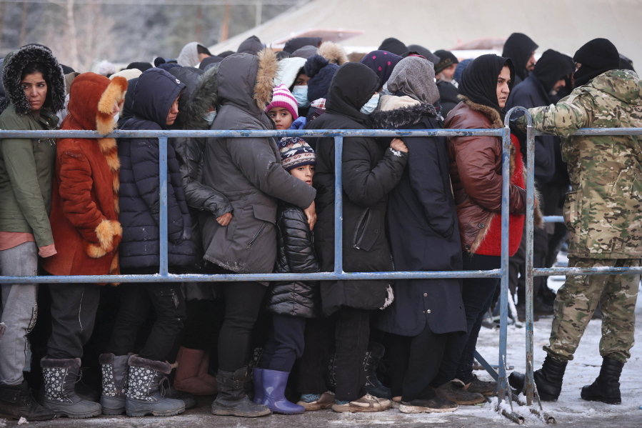 Migrants queue to get hot food in the logistics center of the checkpoint "Bruzgi" at the Belarus-Poland border near Grodno, Belarus, Wednesday, Dec. 1, 2021. The West has accused Belarusian President Alexander Lukashenko of luring thousands of migrants to Belarus with the promise of help to get to Western Europe to use them as pawns to destabilize the 27-nation European Union in retaliation for its sanctions on his authoritarian government. Belarus denies engineering the crisis.