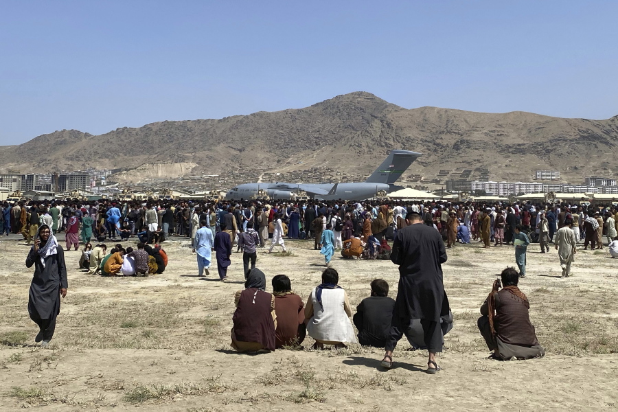 FILE - Hundreds of people gather near a U.S. Air Force C-17 transport plane at a perimeter at the international airport in Kabul, Afghanistan, on Aug. 16, 2021. A whistleblower has alleged that Britain's Foreign Office abandoned many of the nation's allies in Afghanistan and left them to the mercy of the Taliban during the fall of the capital, Kabul, because of a dysfunctional and arbitrary evacuation effort.