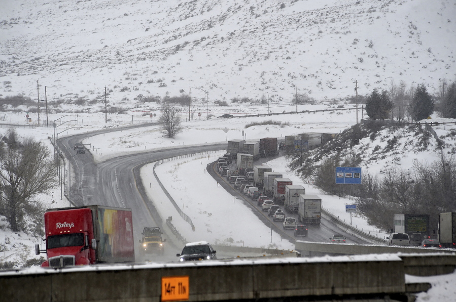 A truck delivering food to Reno, Nev., is seen heading east on I-80 as traffic heading west gets backed up as it approaches a chain control checkpoint near Verdi, Nev., Wednesday, Dec. 29, 2021. More snow and rain fell on California on Wednesday, causing travel disruptions on mountain routes and raising the risk of debris flows from wildfire burn scars. Major highways through the snow-blanketed Sierra Nevada remained open, but chain requirements were in effect in many areas.