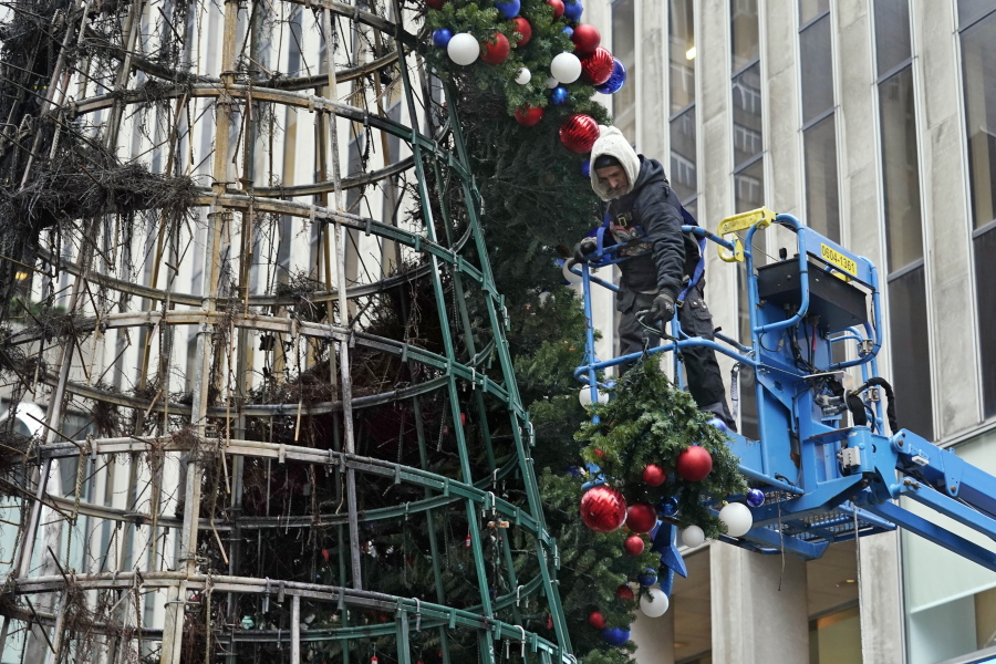 A worker disassembles a Christmas tree outside Fox News headquarters, in New York, Wednesday, Dec. 8, 2021. Police say a man is facing charges including arson for setting fire to a 50-foot Christmas tree in front of Fox News headquarters in midtown Manhattan. The tree outside of the News Corp. building that houses Fox News, The Wall Street Journal and the New York Post caught fire early Wednesday.