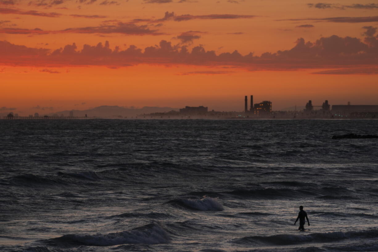 FILE - A man wades into the ocean at sunset, Tuesday, June 22, 2021, in Newport Beach, Calif. In a report released Wednesday, Dec. 8, 2021, the National Academy of Sciences says to fight climate change the world needs to look into the idea of making the oceans suck up more carbon dioxide. (AP Photo/Jae C.