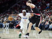 Los Angeles Clippers guard Reggie Jackson, left, dribbles around Portland Trail Blazers center Cody Zeller during the first half of an NBA basketball game in Portland, Ore., Monday, Dec. 6, 2021.