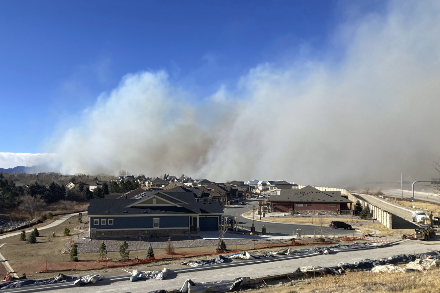 Smoke from a wildfire rises in the background, Thursday, Dec. 30, 2021, in Superior, Colo. All 13,000 residents of the northern Colorado town were ordered to evacuate Thursday because of a wildfire driven by strong winds.