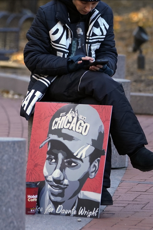 A lone demonstrator sits on a cement barrier with a Daunte Wright poster, Thursday, Dec. 2, 2021, outside the Hennepin County Government Center in Minneapolis as jury selection enters the third day for former suburban Minneapolis police officer Kim Potter. Potter, who is white, is charged with manslaughter in the April 11 shooting of Wright, a 20-year-old Black motorist, following a traffic stop in Brooklyn Center.