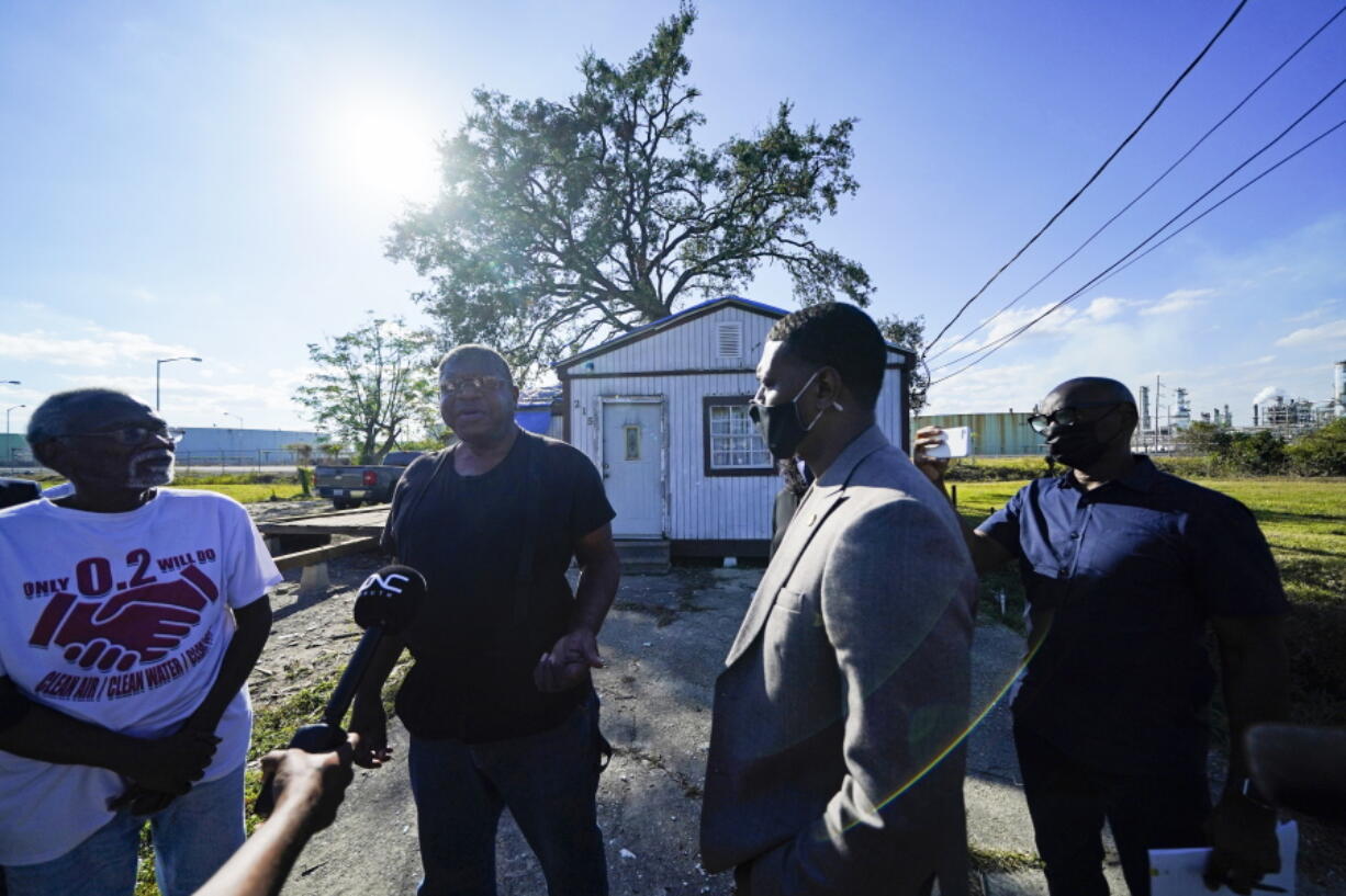 EPA Administrator Michael Regan, second right, talks with Michael Coleman, second left, in front of his house, which abuts the Marathon Petroleum Refinery and a Cargill grain depot, as he tours Reserve, La., Tuesday, Nov. 16, 2021. Coleman's house is the last one standing on his tiny street, squeezed between a sprawling oil refinery whose sounds and smells keep him up at night and a massive grain elevator that spews dust that covers his pickup and, he says, exacerbates his breathing problems.