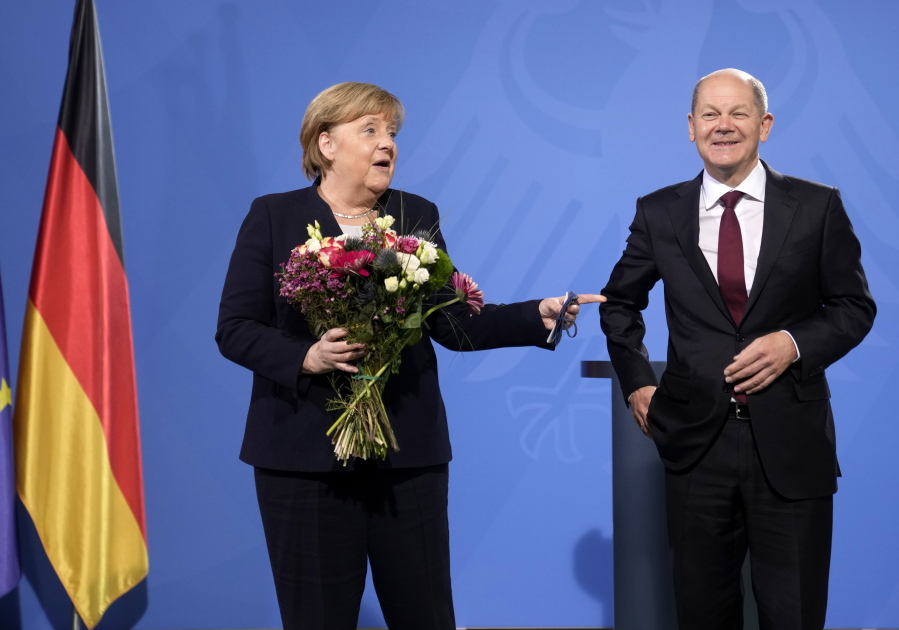 New elected German Chancellor Olaf Scholz, right, has given flowers to former Chancellor Angela Merkel during a handover ceremony in the chancellery in Berlin, Wednesday, Dec. 8, 2021.