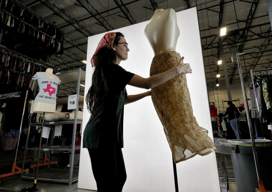 FILE - Samantha Estes prepares garments to be photographed at the ThredUp sorting facility in Phoenix on March 12, 2019. Resale has taken off among some looking to save the planet and spend less on gifts during the most wasteful time of the year _ the December holidays. This year's supply chain delays have provided extra motivation.