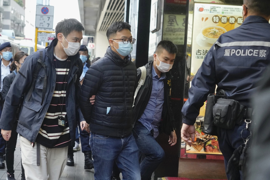 Editor of "Stand News" Patrick Lam, second from left, is arrested by police officers in Hong Kong, Wednesday, Dec. 29, 2021. Hong Kong police say they have arrested seveal current and former staff members of the online media company for conspiracy to publish a seditious publication.
