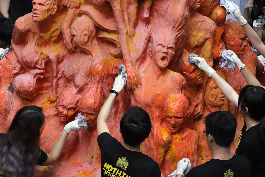 FILE - University students clean the "Pillar of Shame" statue, a memorial for those killed in the 1989 Tiananmen crackdown, at the University of Hong Kong, June 4, 2019. For Hong Kong's pro-democracy movement, 2021 has been a year in which the city's authorities and the central government in Beijing stamped out nearly everything it had stood for.