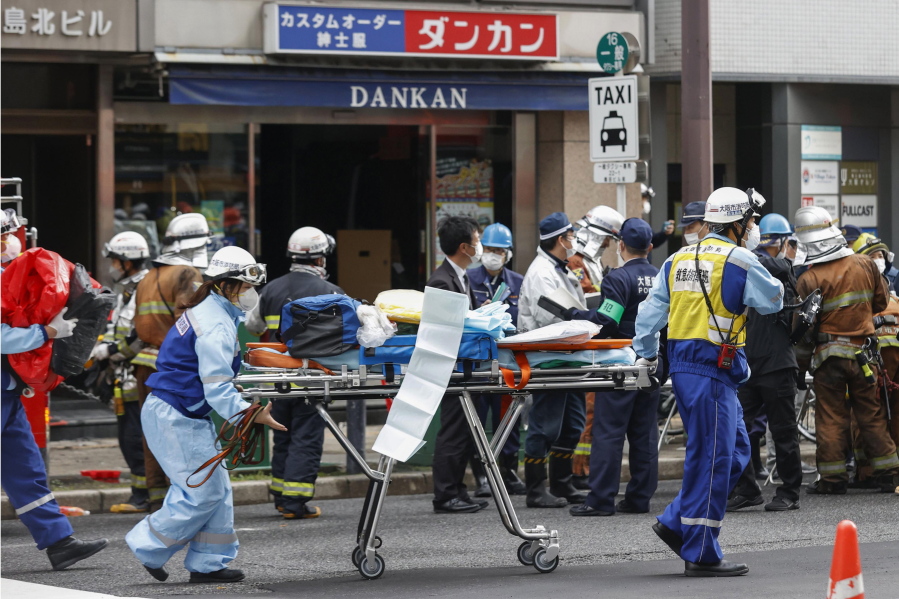 First responders carry a stretcher after a deadly fire at an eight-story building in a major business, shopping and entertainment district in Osaka, western Japan, Friday, Dec. 17, 2021. More than 20 people were feared dead after the fire broke out Friday in the building in Osaka, officials said, and police were investigating arson as a possible cause.