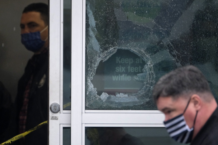 Police officers work near a broken glass door at the scene where two people were struck by gunfire in a shooting at a Burlington store -- part of a chain formerly known as Burlington Coat Factory in North Hollywood, Calif., Thursday, Dec. 23, 2021. (AP Photo/Ringo H.W.