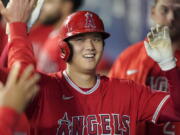 FILE - Los Angeles Angels' Shohei Ohtani is greeted in the dugout after he hit a solo home run during the first inning of a baseball game against the Seattle Mariners, Sunday, Oct. 3, 2021, in Seattle. Ohtani, the Los Angeles Angels' two-way superstar, is the winner of The Associated Press' Male Athlete of the Year award. (AP Photo/Ted S.