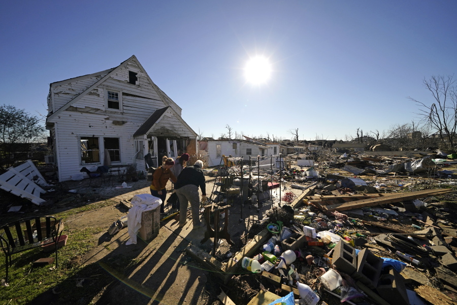 Volunteers, mostly employees from the Mayfield Consumer Products factory, help salvage possessions from the destroyed home of Martha Thomas, in the aftermath of tornadoes that tore through the region several days earlier, in Mayfield, Ky., Monday, Dec. 13, 2021.