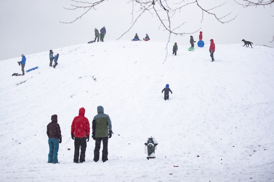 People enjoy Kite Hill in the snow at Gas Works Park Sunday, Dec. 26, 2021, in Seattle. Snow is blanketing parts of the Pacific Northwest because of unusually cold temperatures.  Seattle got between 3 and 5 inches of snow as of Sunday morning.