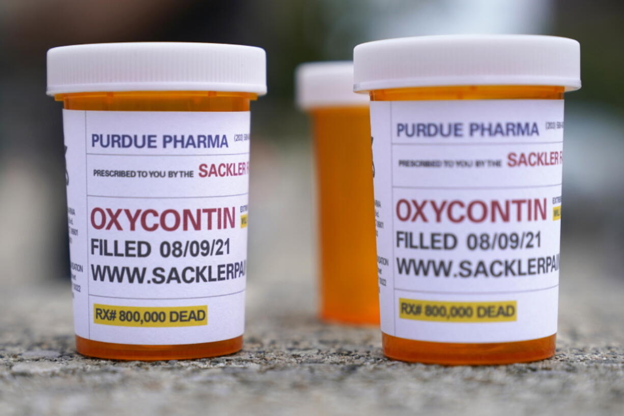 FILE - In this Aug. 9, 2021, file photo, fake pill bottles with messages about OxyContin maker Purdue Pharma are displayed during a protest outside the courthouse where the bankruptcy of the company is taking place in White Plains, N.Y.  A federal judge on Thursday, Dec. 16, 2021, has rejected OxyContin maker Purdue Pharma's bankruptcy settlement of thousands of lawsuits over the opioid epidemic because of a provision that would protect members of the Sackler family from facing litigation of their own.