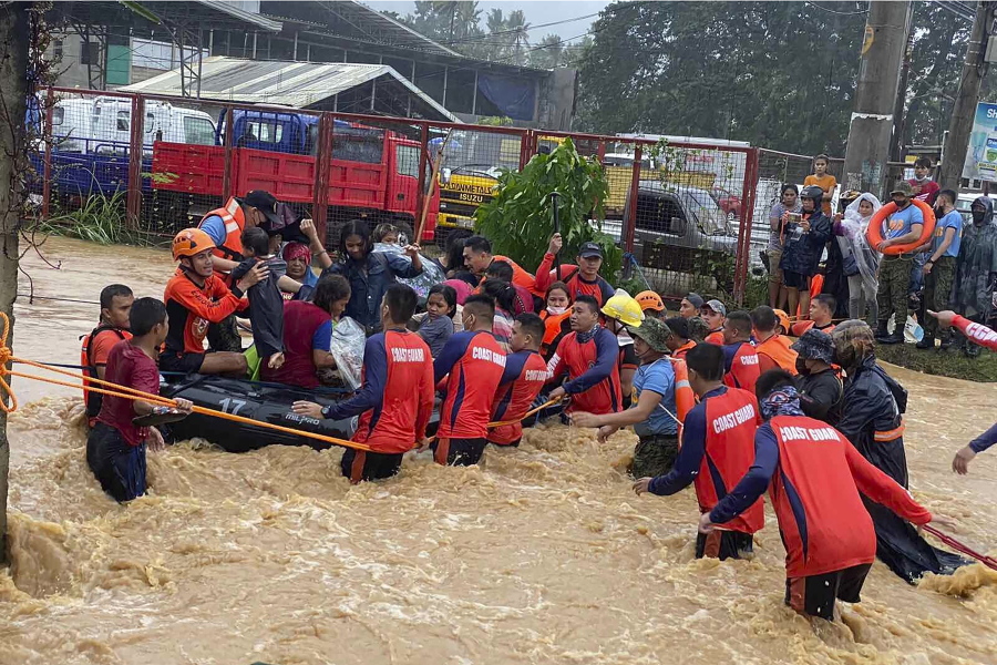 In this handout photo provided by the Philippine Coast Guard, rescuers assist residents over floodwaters caused by Typhoon Rai as they are evacuated to higher ground in Cagayan de Oro City, southern Philippines, Thursday, Dec. 16, 2021. Tens of thousands of people were being evacuated to safety in the southern and central Philippines as Typhoon Rai approached Thursday at a time when authorities were warning the public to avoid crowds after the first infections caused by the omicron strain of the coronavirus were reported in the country, officials said.