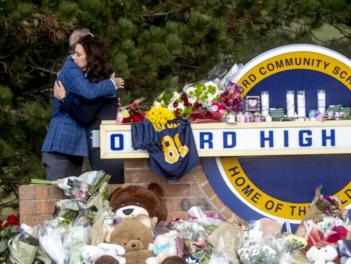 Gov. Gretchen Whitmer embraces Oakland County Executive Dave Coulter as the two leave flowers and pay their respects Thursday morning, Dec. 2, 2021 at Oxford High School in Oxford, Mich.