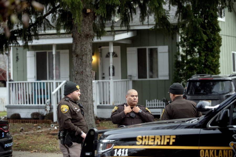 FILE - Three Oakland County Sheriff's deputies survey the grounds outside of the Crumbley residence while seeking James and Jennifer Crumbley, parents of Oxford High School shooter Ethan Crumbley, Dec. 3, 2021, in Oxford, Mich. A Detroit-area artist whose studio was where the parents of the Oxford High School student charged in a deadly shooting were found by police is cooperating with authorities and didn't know the couple had stayed overnight, his attorney said Sunday, Dec, 5, 2021.