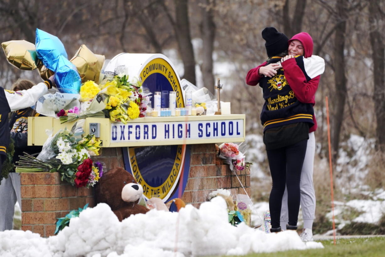 FILE -- Students hug at a memorial at Oxford High School in Oxford, Mich., Dec. 1, 2021.  School systems nationwide rely on high-level expertise from the U.S. Secret Service and others as they work to stay vigilant for signs of potential student violence, training staff, surveilling social media and urging others to tip them off. However, when it comes to deciding how to respond to a possible threat, it's the local educators who make the call.