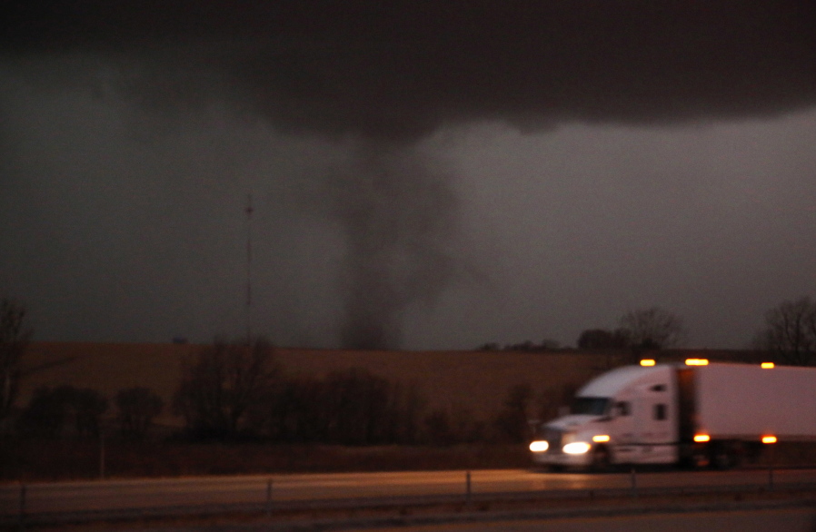 FILE- A tornado approaches Interstate 80 near Atlantic, Iowa, as a semi truck rolls eastward on Wednesday, Dec. 15, 2021. The National Weather Service has declared the series of thunderstorms and tornadoes that swept across the Great Plains and upper Midwest on Dec. 15 as a serial derecho, a rare event featuring a very lengthy and wide line of storms. The service said it was the first-ever serial derecho in December in the U.S.