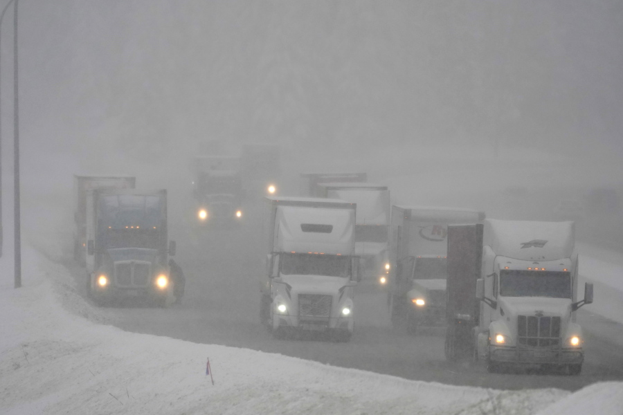 Trucks drive on a snow-covered stretch of eastbound Interstate Highway 90, Thursday, Dec. 9, 2021, as snow falls near Snoqualmie Pass in Washington state. More U.S. drivers could find themselves stuck on snowy highways or have their travel delayed this winter due to a shortage of snowplow drivers as some states are having trouble finding enough people willing to take the jobs. (AP Photo/Ted S.