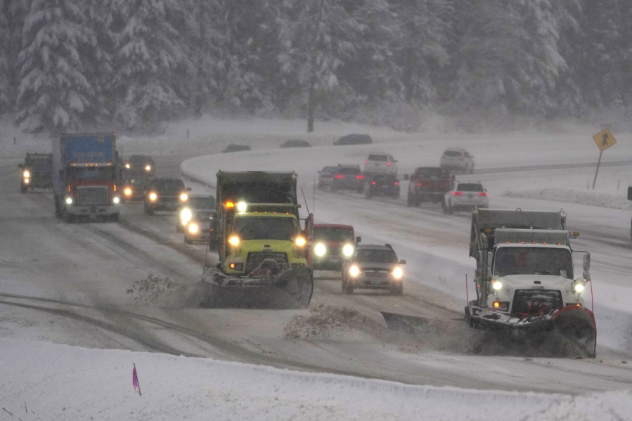 Washington Dept. of Transportation snow plows work on a stretch of eastbound Interstate Highway 90, Thursday, Dec. 9, 2021, as snow falls near Snoqualmie Pass in Washington state. More U.S. drivers could find themselves stuck on snowy highways or have their travel delayed this winter due to a shortage of snowplow drivers as some states are having trouble finding enough people willing to take the jobs. (AP Photo/Ted S.
