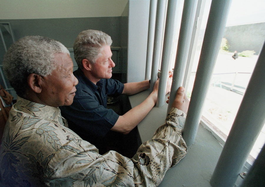 FILE - Nelson Mandela, left, and former US president Bill Clinton look to the outside from Mandela's Robben Island prison cell in Cape Town, South Africa, March 27, 1998. A South African Cabinet minister on Friday Dec. 24, 2021, urged the cancellation of an upcoming U.S. auction of a key to the Robben Island prison cell where Nelson Mandela, the country's first Black president, was long jailed for his opposition to apartheid.