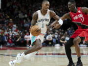 San Antonio Spurs guard Lonnie Walker IV, left, dribbles past Portland Trail Blazers forward Tony Snell during the first half of an NBA basketball game in Portland, Ore., Thursday, Dec. 2, 2021.