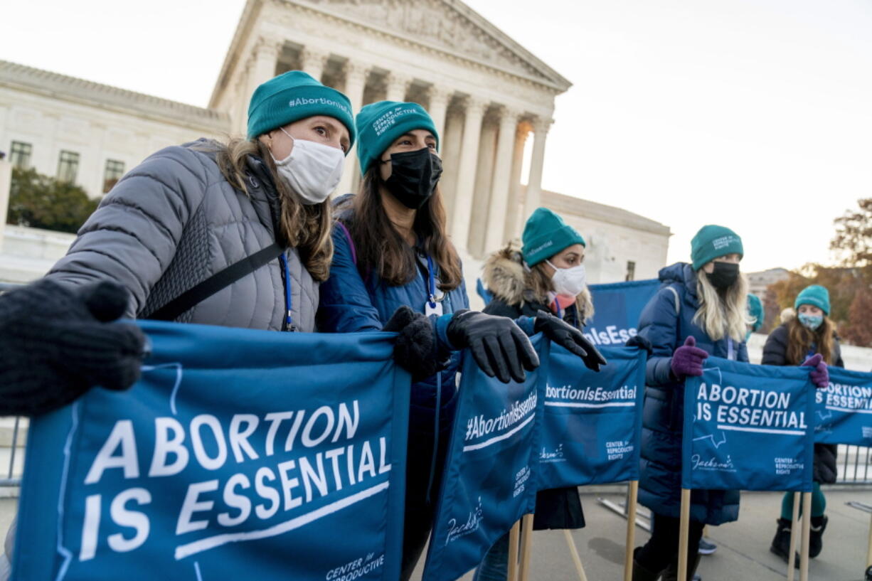 Abortion rights advocates hold signs that read "Abortion is Essential" as they demonstrate in front of the U.S. Supreme Court, Wednesday, Dec. 1, 2021, in Washington, as the court hears arguments in a case from Mississippi, where a 2018 law would ban abortions after 15 weeks of pregnancy, well before viability.
