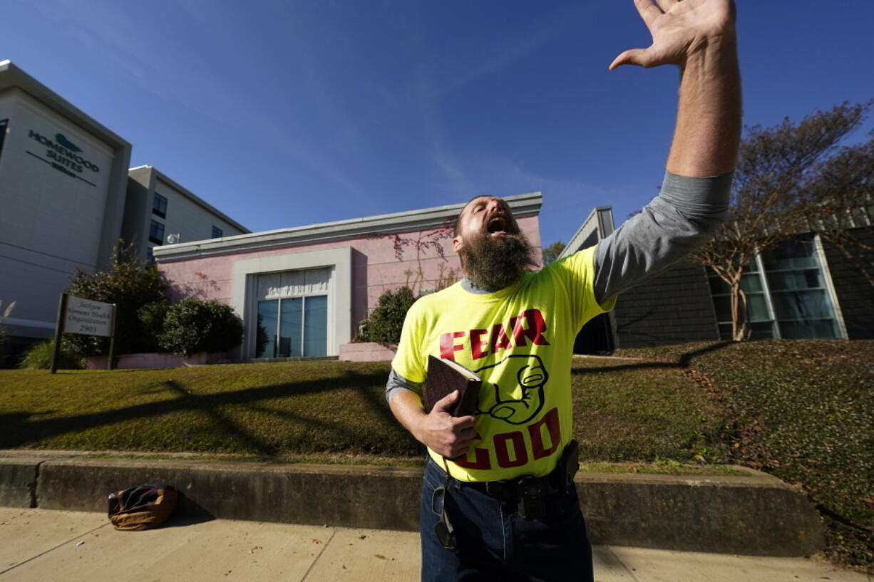 Allen Siders, an anti-abortion activist, preaches outside of the Jackson Women's Health Organization, a state-licensed abortion clinic in Jackson, Miss., Tuesday, Nov. 30, 2021. A small group of anti-abortion activists stood outside the clinic in an effort to dissuade patients from entering. On Wednesday, the U.S. Supreme Court will hear a case that directly challenges the constitutional right to an abortion established nearly 50 years ago. (AP Photo/Rogelio V.