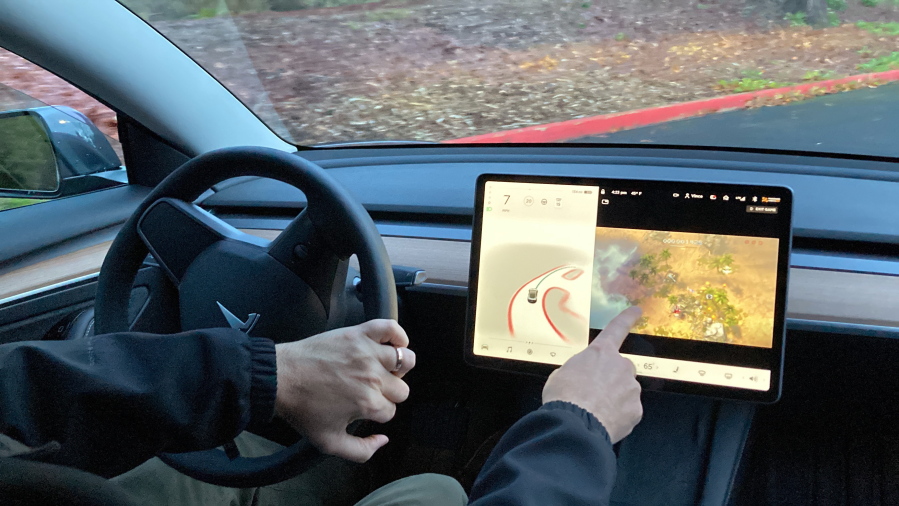 FILE - Vince Patton, a new Tesla owner, demonstrates on Dec. 8, 2021, on a closed course in Portland, Ore., how he can play video games on the vehicle's console while driving. The U.S. has opened a formal investigation into a report that Tesla vehicles allow people to play video games on a center touch screen while they are driving.