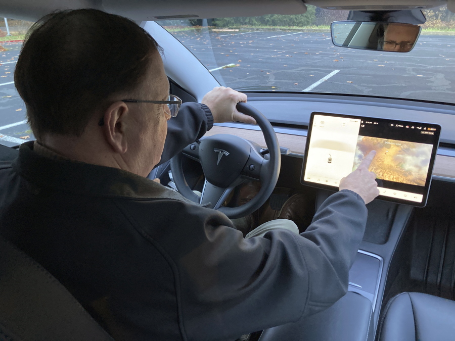 Vince Patton, a new Tesla owner, demonstrates on Wednesday, Dec. 8, 2021, on a closed course in Portland, Ore., how he can play video games on the vehicle's console while driving. Patton, of Portland, Ore., filed a complaint with federal regulators after discovering the feature in his new car.