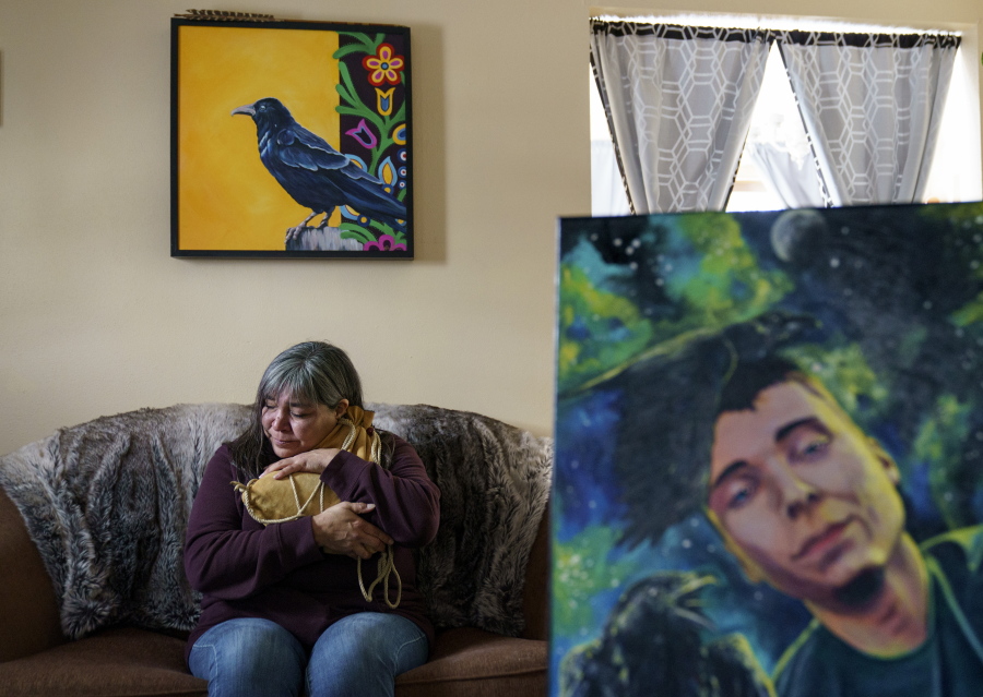 Rachel Taylor clutches a buckskin satchel filled with the ashes of her son, Kyle "Little Crow" Domrese, pictured at right, who died of an overdose, as she sits in the home they shared in Bemidji, Minn., Wednesday, Nov. 17, 2021. Just weeks remained until the anniversary of the day she opened his bedroom door and found her son face-down on his bed, one of more than 100,000 Americans lost in a year to overdoses as the COVID-19 pandemic aggravated America's addiction disaster. The death rate from drug overdoses for Native Americans has surpassed white people and is now the highest in the nation.