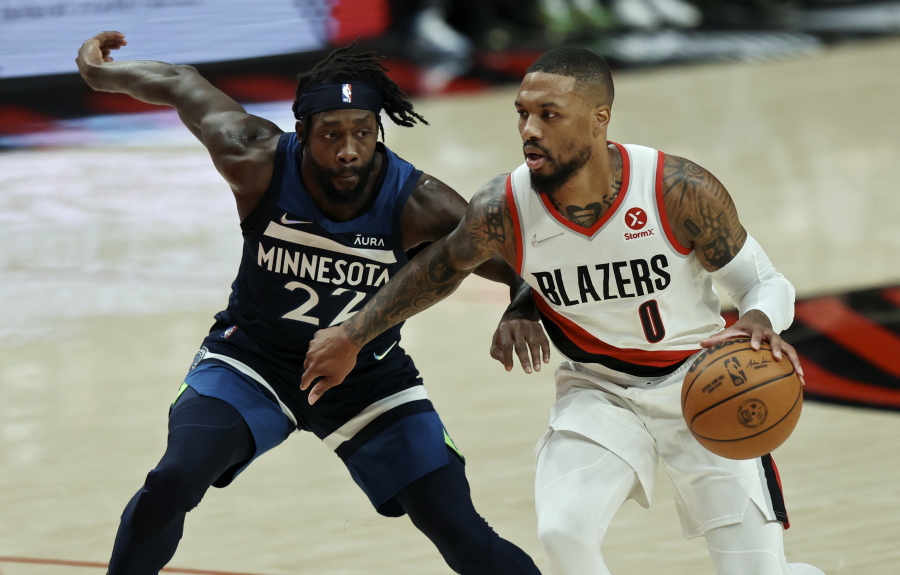 Portland Trail Blazers guard Damian Lillard, left, drives against Minnesota Timberwolves guard Patrick Beverley, left, during the first half of an NBA basketball game in Portland, Ore., Sunday, Dec. 12, 2021.