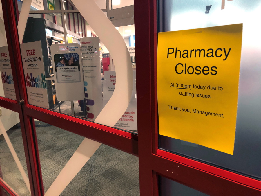 A sign is posted outside a CVS pharmacy on Thursday, Dec. 2, 2021 in Indianapolis. A rush of vaccine-seeking customers and staff shortages are squeezing drugstores around the country. That has led to frazzled workers and even temporary pharmacy closures.