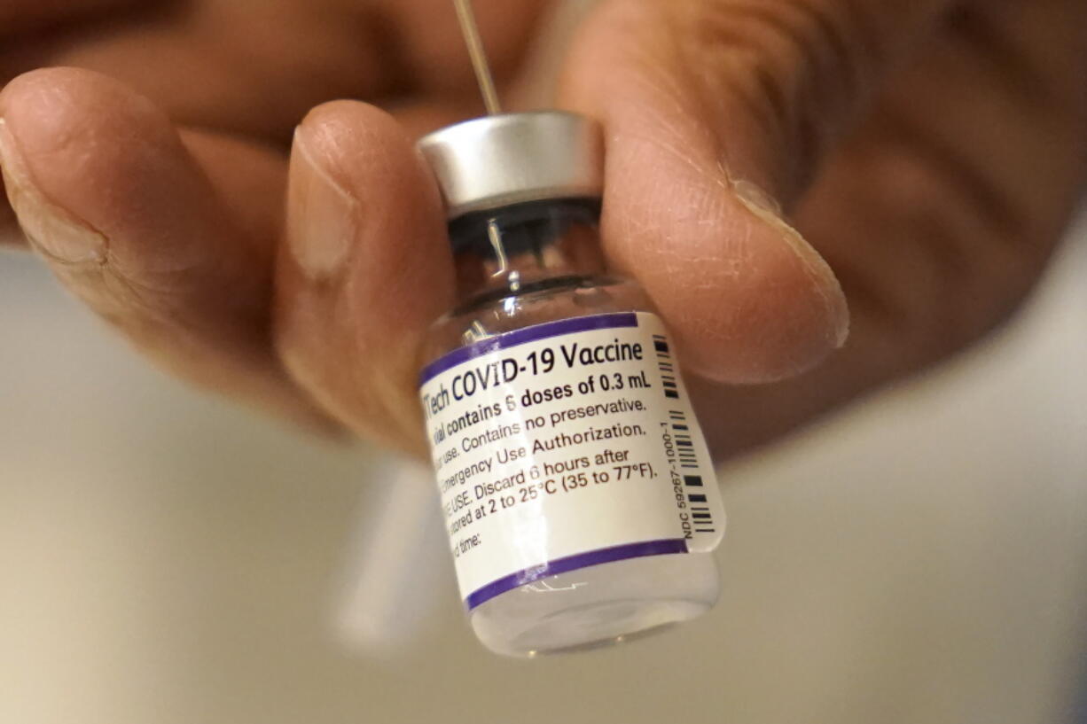 FILE - Dr. Manjul Shukla transfers Pfizer COVID-19 vaccine into a syringe, Thursday, Dec. 2, 2021, at a mobile vaccination clinic in Worcester, Mass. Pfizer said Wednesday, Dec. 8, 2021, that a booster dose of its COVID-19 vaccine may protect against the new omicron variant even though the initial two doses appear significantly less effective.