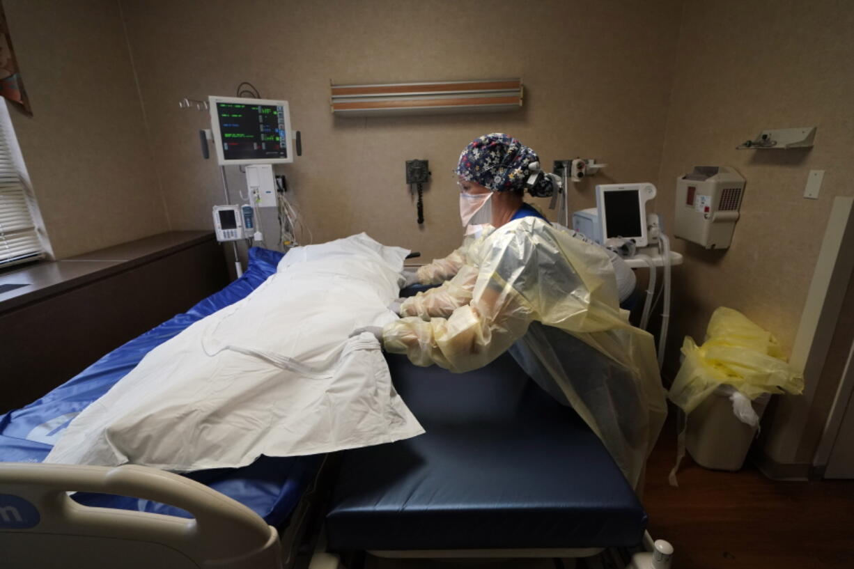 FILE - Medical staff move a COVID-19 patient who died onto a gurney to hand off to a funeral home van, at the Willis-Knighton Medical Center in Shreveport, La., Aug. 18, 2021. The U.S. death toll from COVID-19 topped 800,000, a once-unimaginable figure seen as doubly tragic, given that more than 200,000 of those lives were lost after the vaccine became available practically for the asking.
